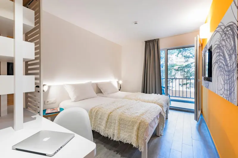 Une chambre lumineuse avec un lit double et un accès à un balcon.