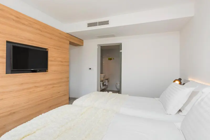 Une chambre lumineuse avec un lit et un téléviseur mural.