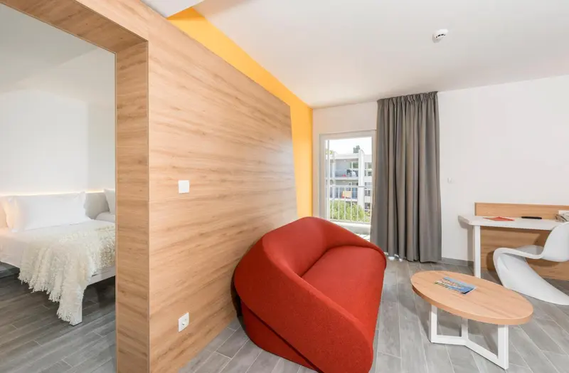 Espace de vie moderne avec un fauteuil rouge et un bureau.