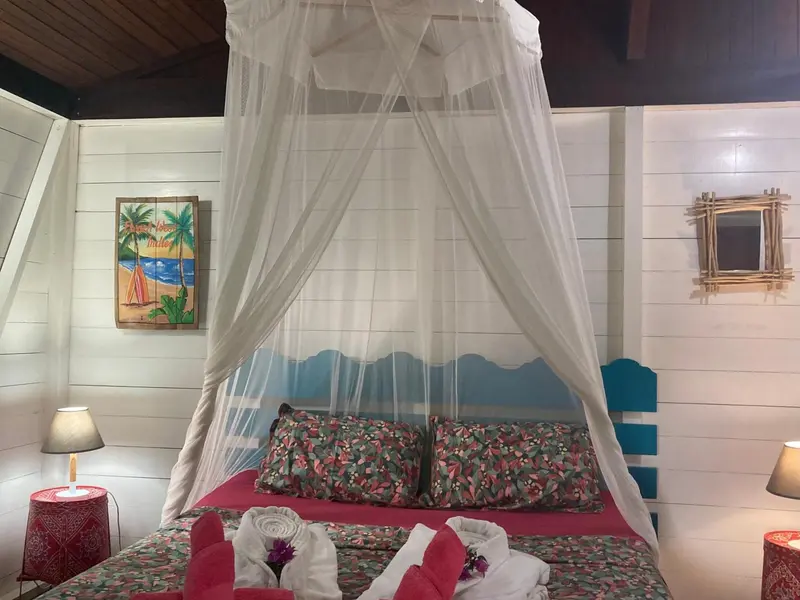 Lit à baldaquin dans une chambre décorée de motifs tropicaux.