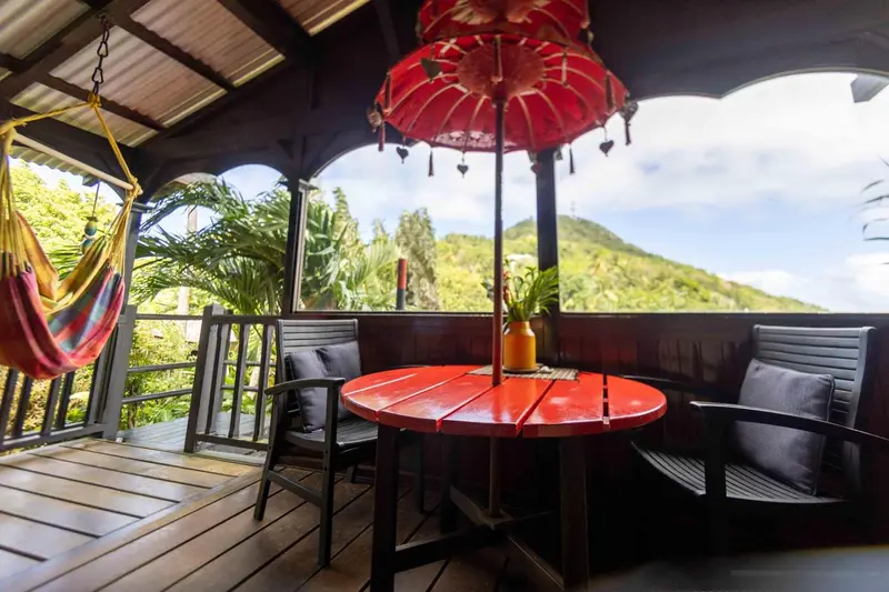 Espace de détente extérieur avec mobilier coloré et vue sur la végétation.
