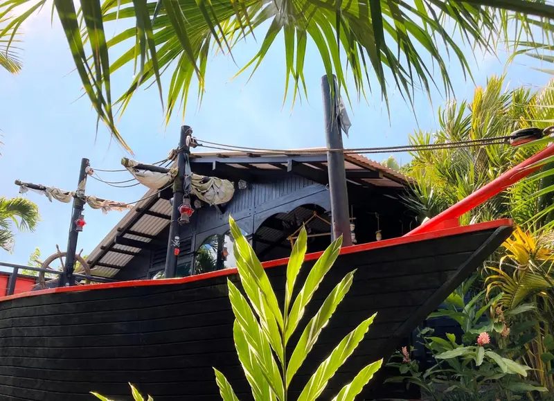Une structure en forme de bateau pirate avec des hamacs et une végétation luxuriante.