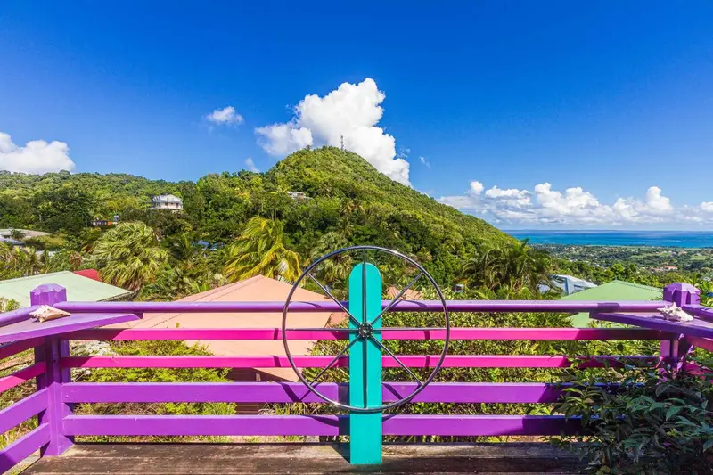 Terrasse colorée avec vue sur une colline verdoyante et la mer.