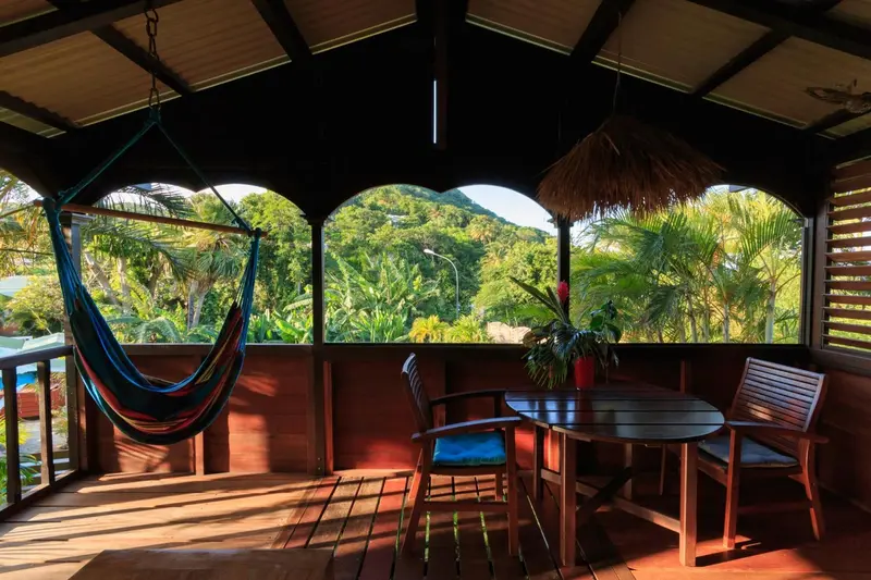 Une terrasse en bois abritée offre une vue sur une végétation luxuriante.