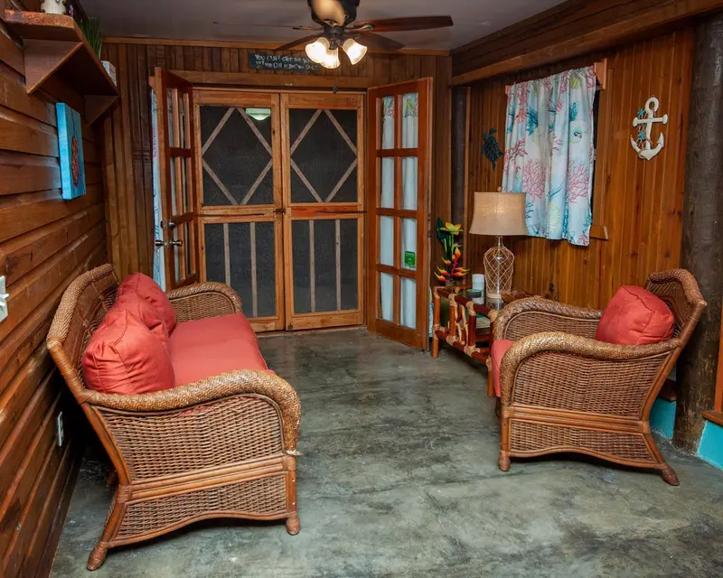 Espace de détente intérieur avec mobilier en rotin et décoration tropicale.