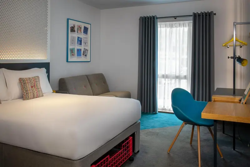Une chambre lumineuse avec un lit, un canapé et un bureau.