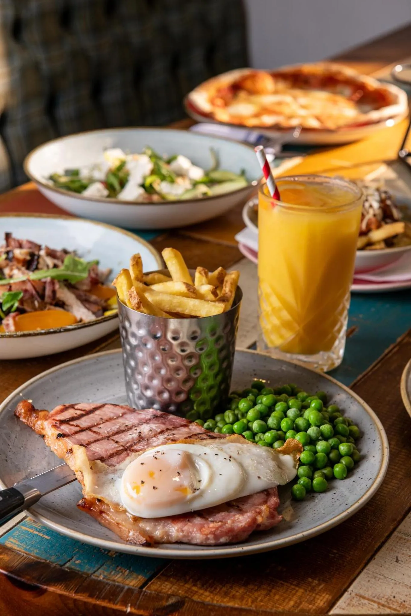 Une table est dressée avec plusieurs plats variés et une boisson orangée.