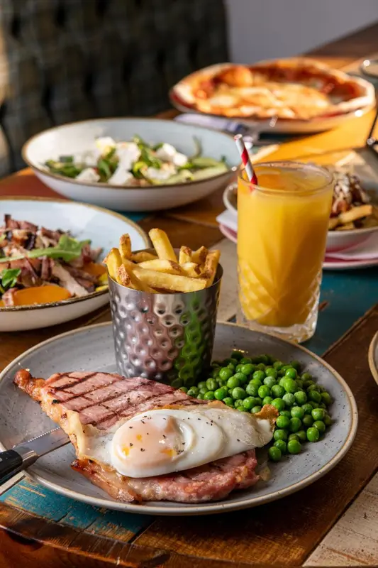 Une table est dressée avec plusieurs plats variés et une boisson orangée.