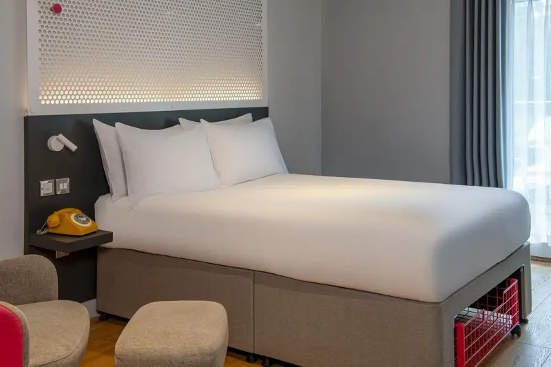 Une chambre d'hôtel moderne avec un grand lit recouvert de draps blancs.