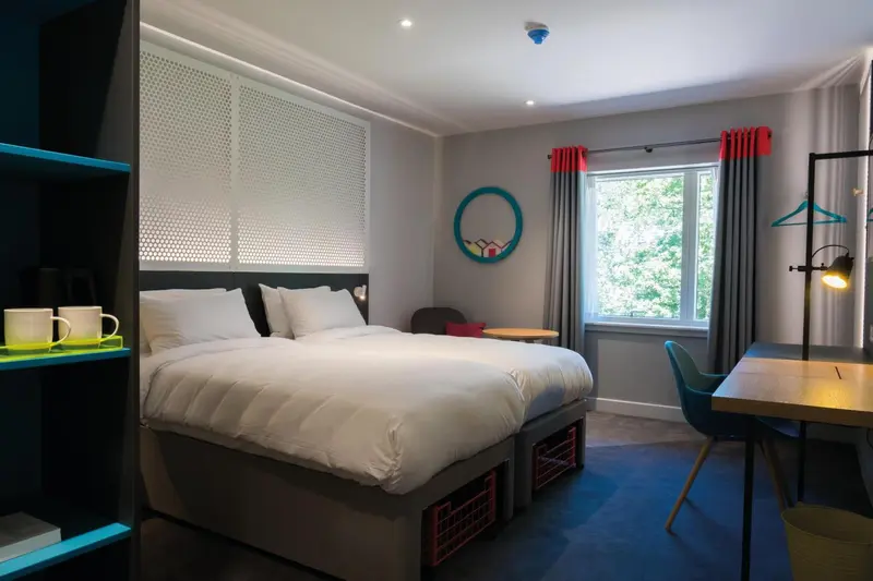 Une chambre d'hôtel moderne avec un lit blanc et un bureau.