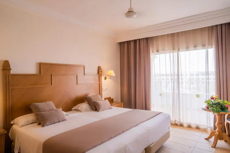 Une chambre lumineuse avec un grand lit et un accès à une terrasse.