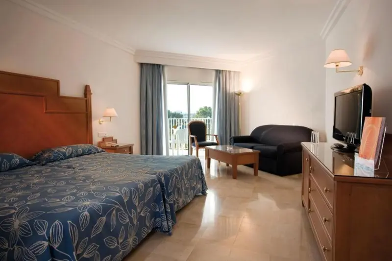 Une chambre lumineuse avec un grand lit et un coin salon.