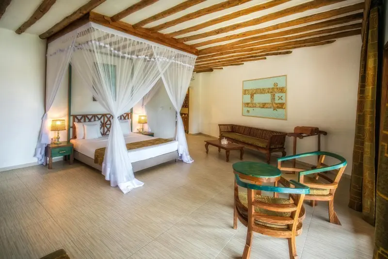 Une chambre lumineuse avec un lit à baldaquin et un coin salon.