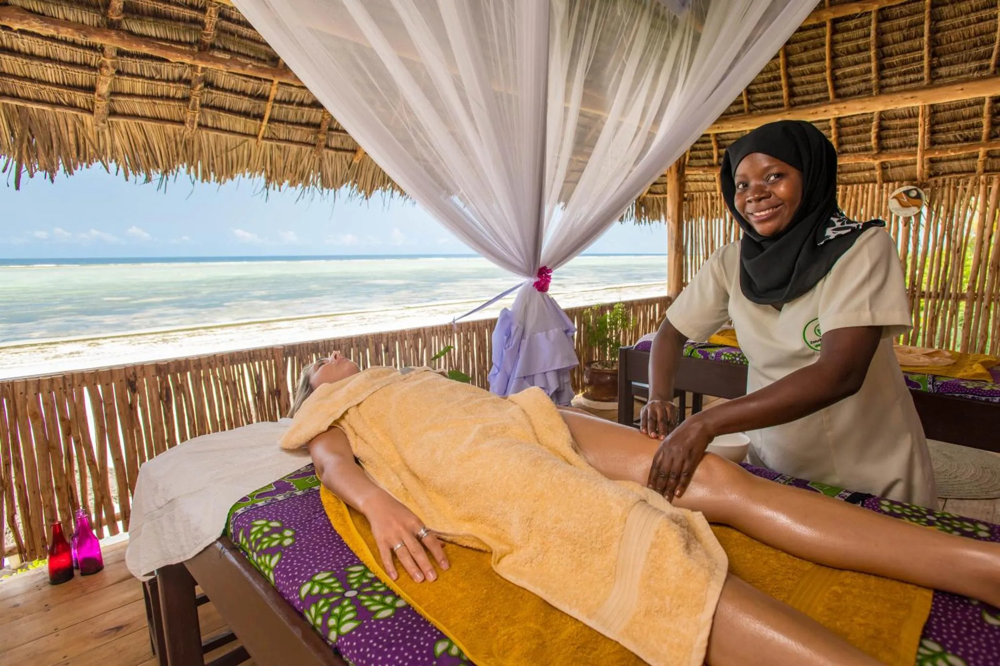 Une femme reçoit un massage sur une table de relaxation en bord de mer.
