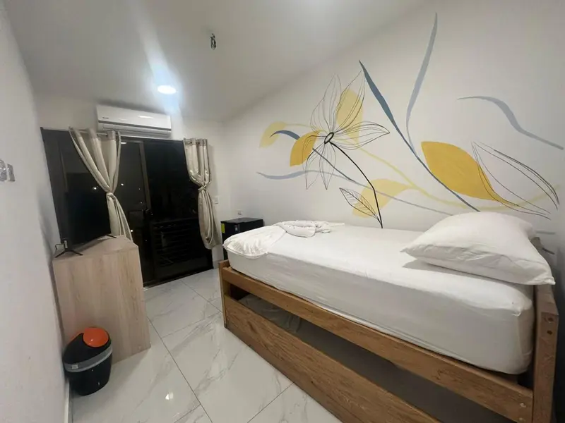 Une chambre lumineuse avec un lit simple et une décoration florale murale.