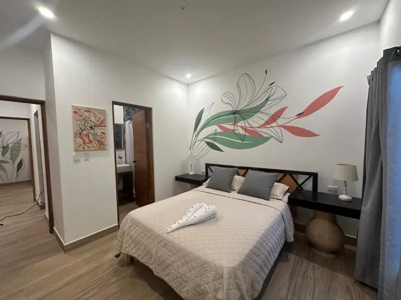 Une chambre lumineuse avec un grand lit et une décoration murale florale.