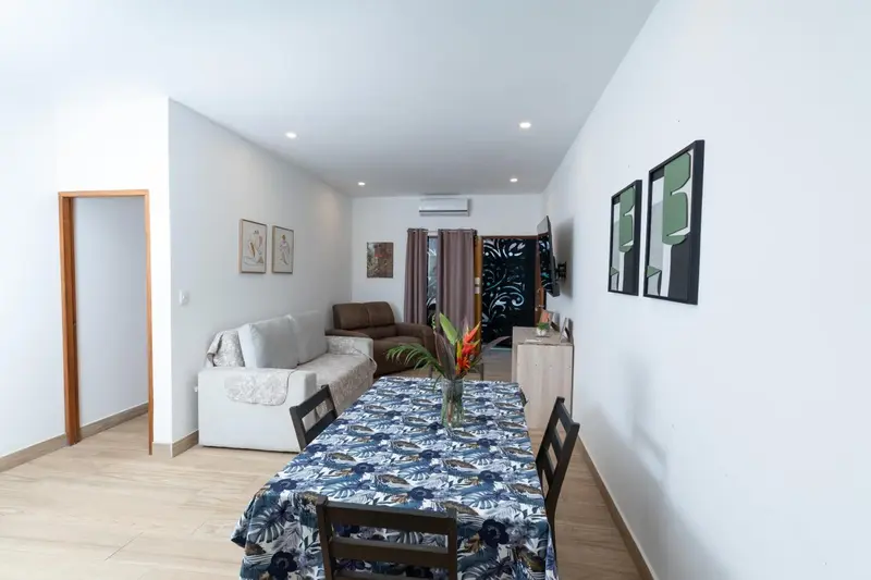 Espace de vie lumineux avec canapé, table à manger et décoration murale.
