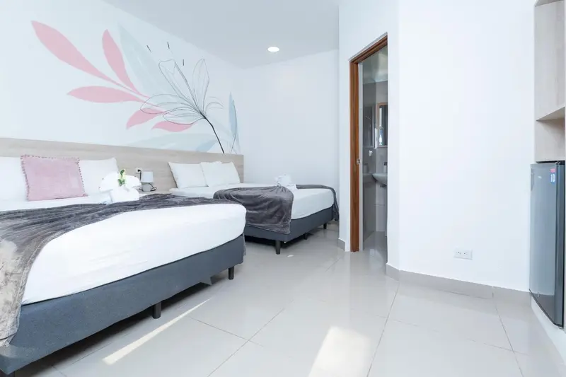 Une chambre lumineuse avec deux lits et une décoration florale au mur.