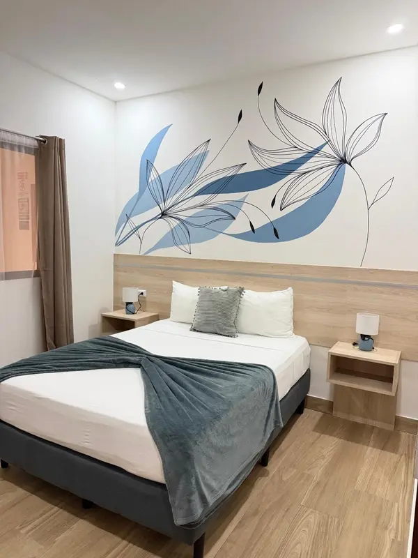 Une chambre lumineuse avec un lit double et une décoration florale murale.