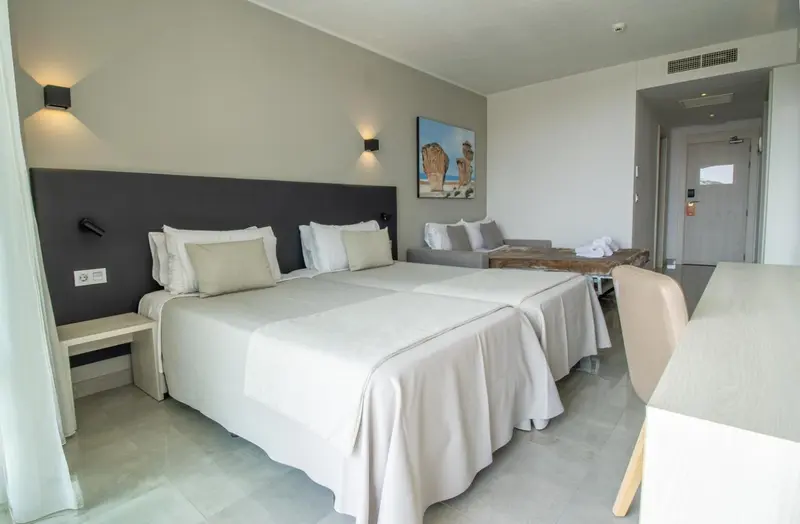 Chambre lumineuse avec un grand lit et un coin salon.