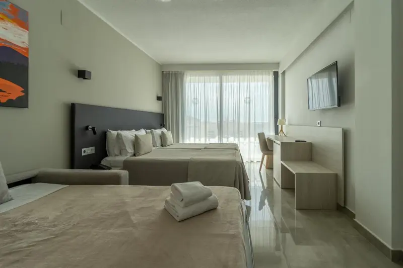 Chambre lumineuse avec deux lits et vue sur l'extérieur.