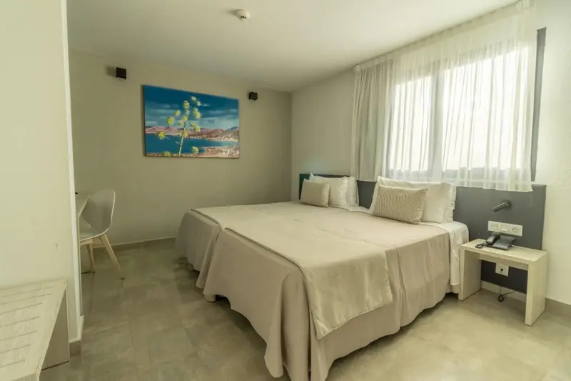 Une chambre lumineuse avec un grand lit et des rideaux blancs.