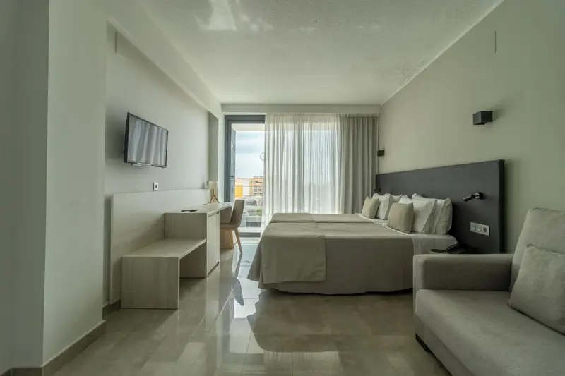 Chambre lumineuse avec un grand lit et un coin salon.