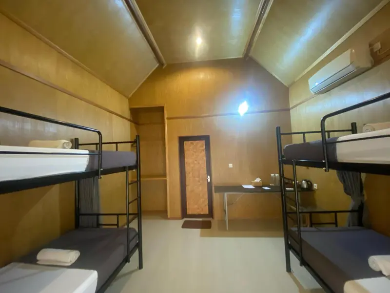 Une chambre avec plusieurs lits superposés et un bureau.