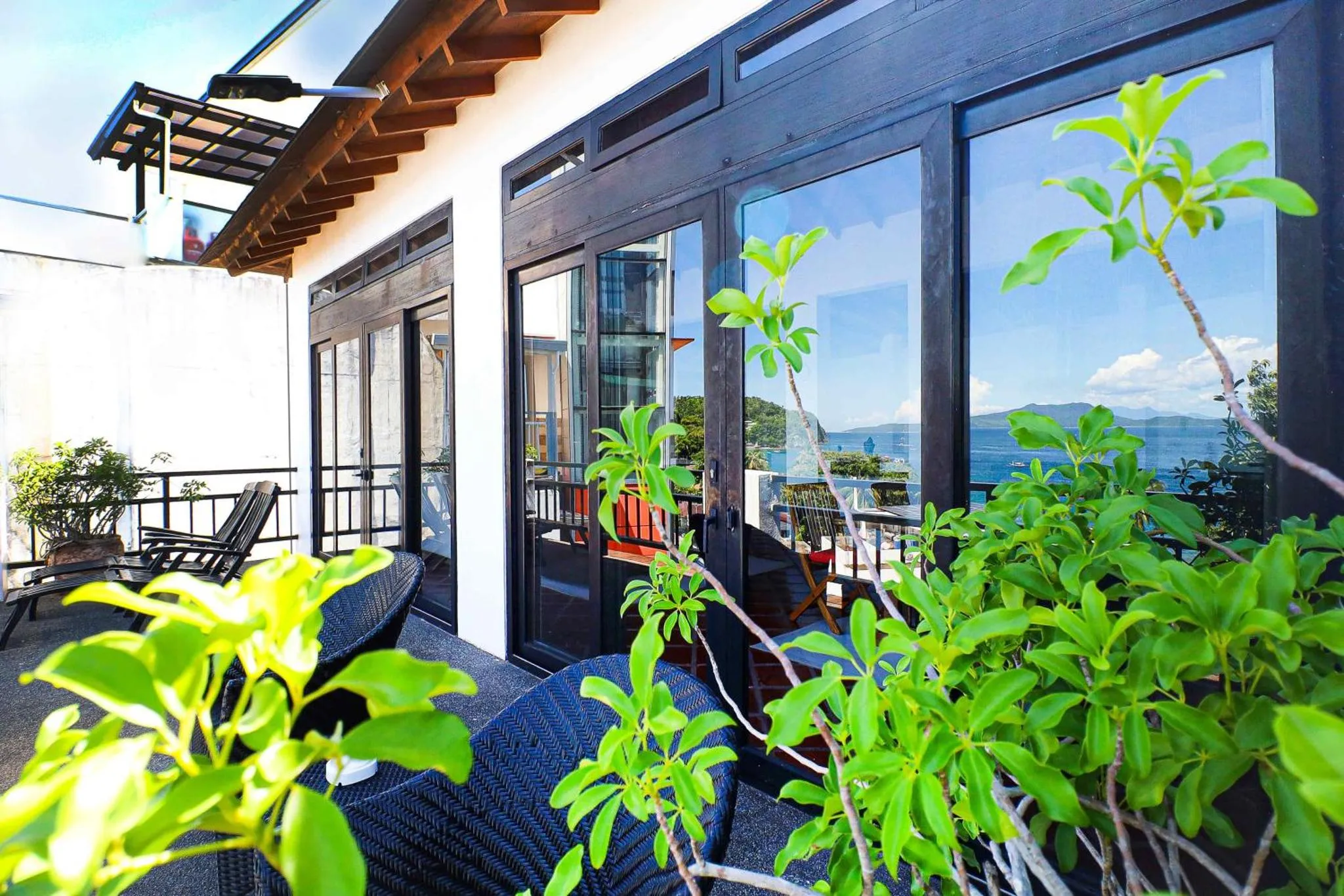 Terrasse ombragée avec mobilier d'extérieur donnant sur une vue mer et montagne.