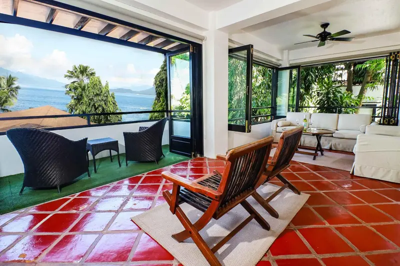 Espace de détente intérieur avec mobilier en rotin et vue sur la mer.