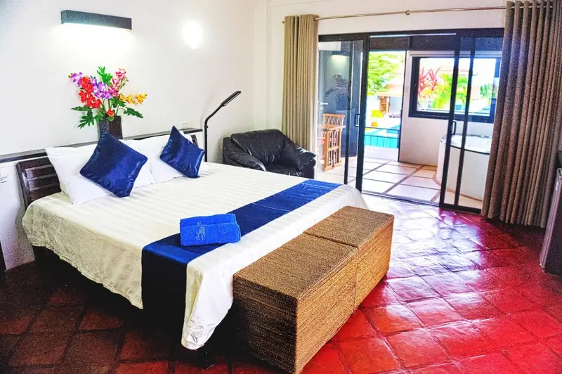 Une chambre avec un grand lit recouvert d'une courtepointe bleue et d'un coffre en osier.