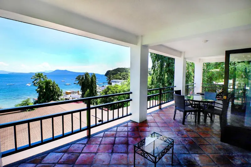 Terrasse carrelée avec mobilier de jardin donnant sur la mer.