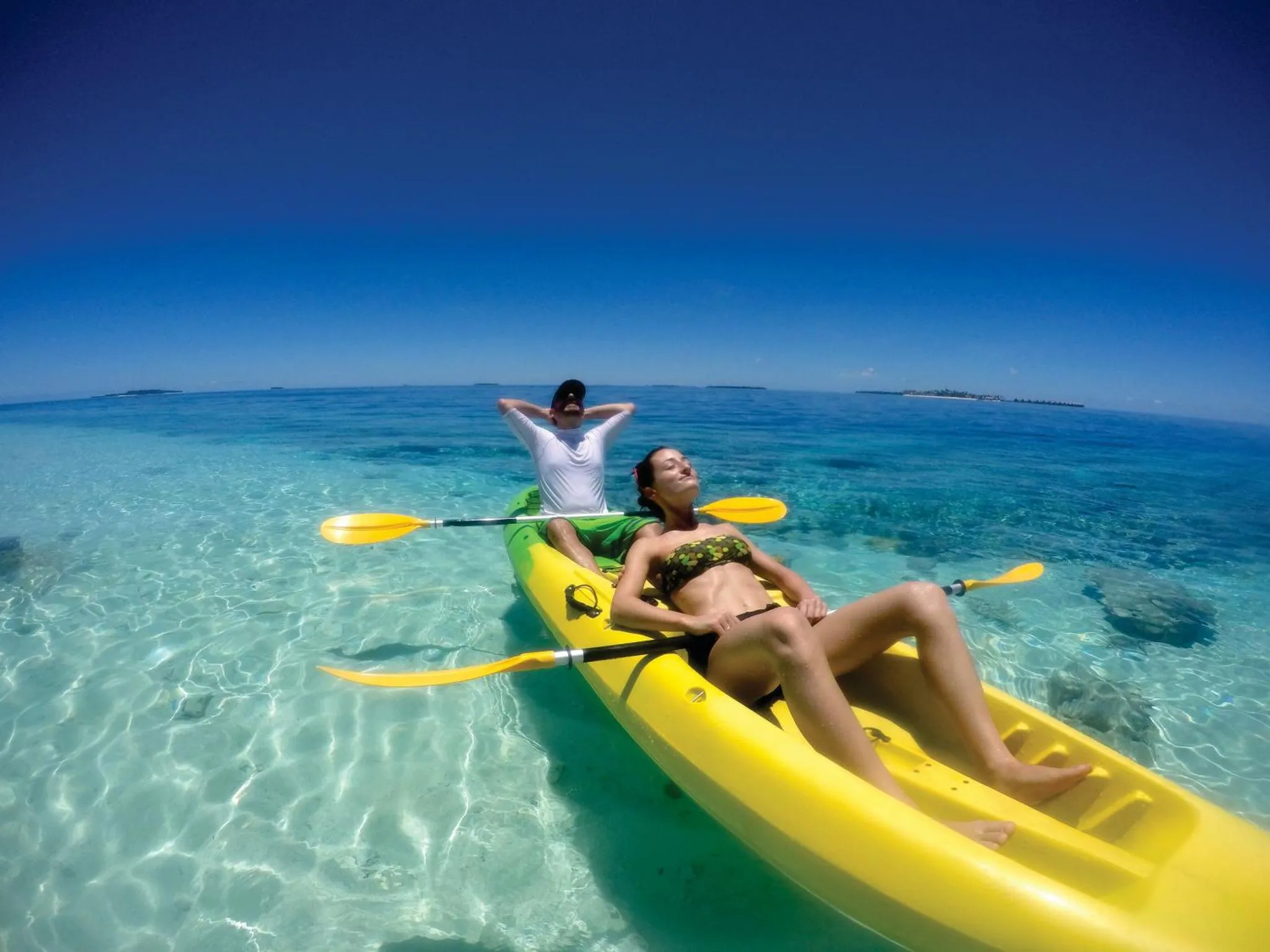 Deux personnes se détendent sur un kayak dans une eau turquoise.