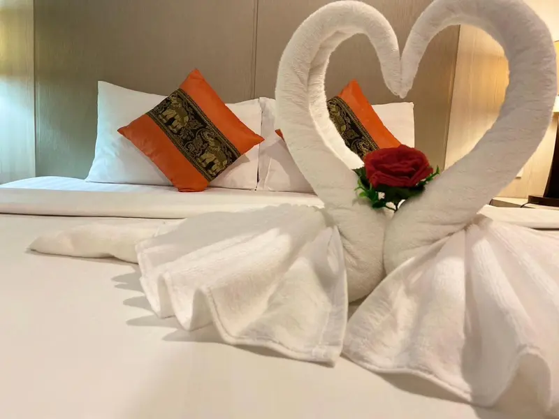 Un lit soigneusement fait avec des serviettes en forme de cygnes et de cœur.