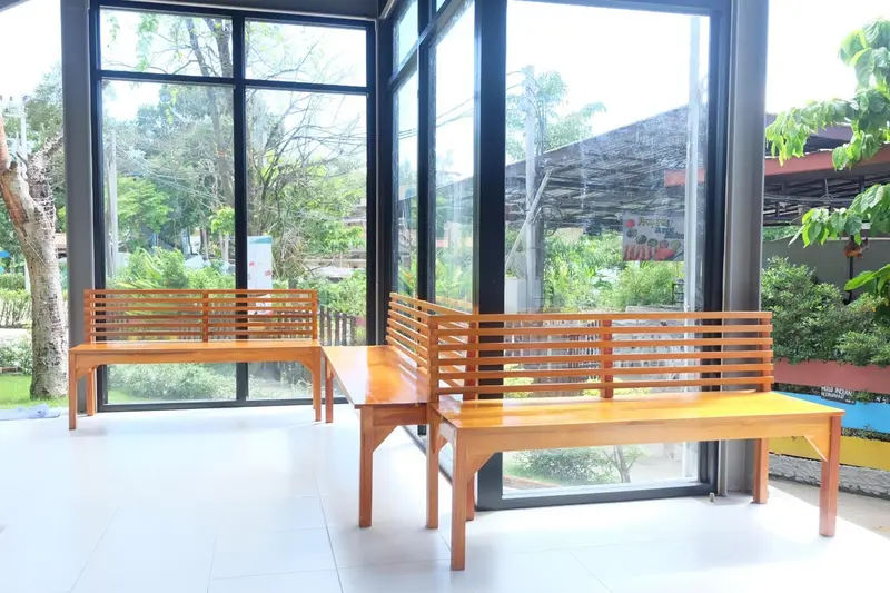 Espace de repos avec des bancs en bois devant de grandes baies vitrées.