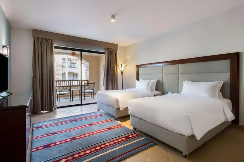 Chambre avec deux lits et accès à une terrasse.