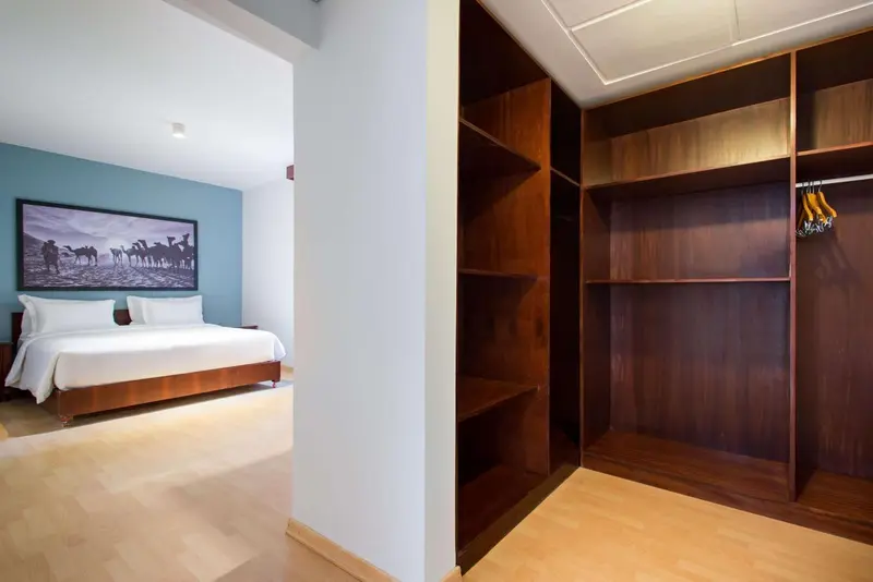 Une chambre lumineuse avec un grand lit et un placard intégré en bois.