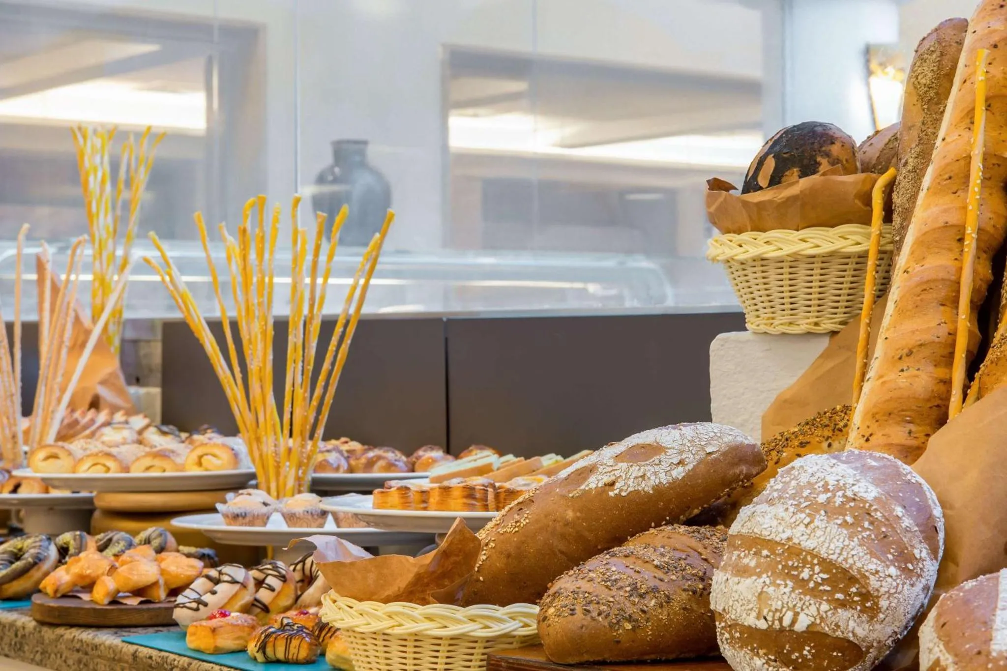 Présentation de viennoiseries et de pains variés sur un buffet.
