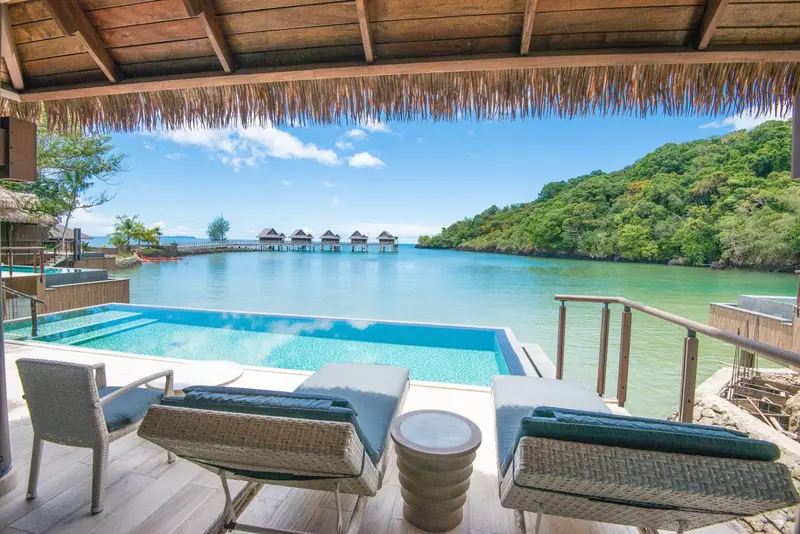 Terrasse avec piscine privative donnant sur une baie turquoise.