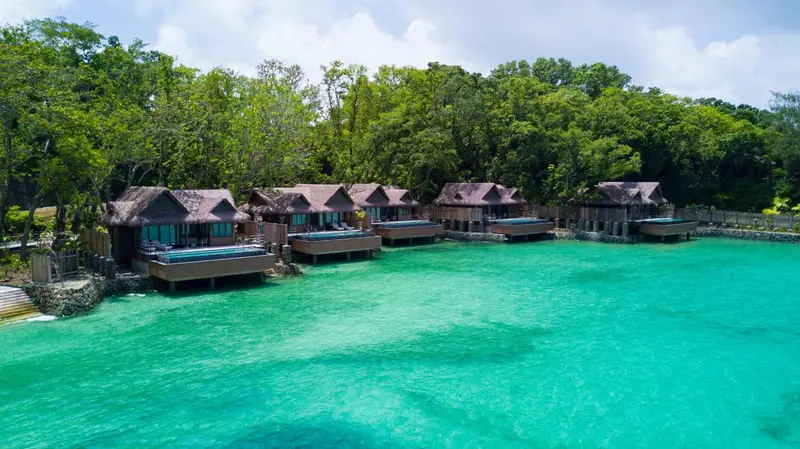 Cabanes sur pilotis au bord d'une eau turquoise et claire.