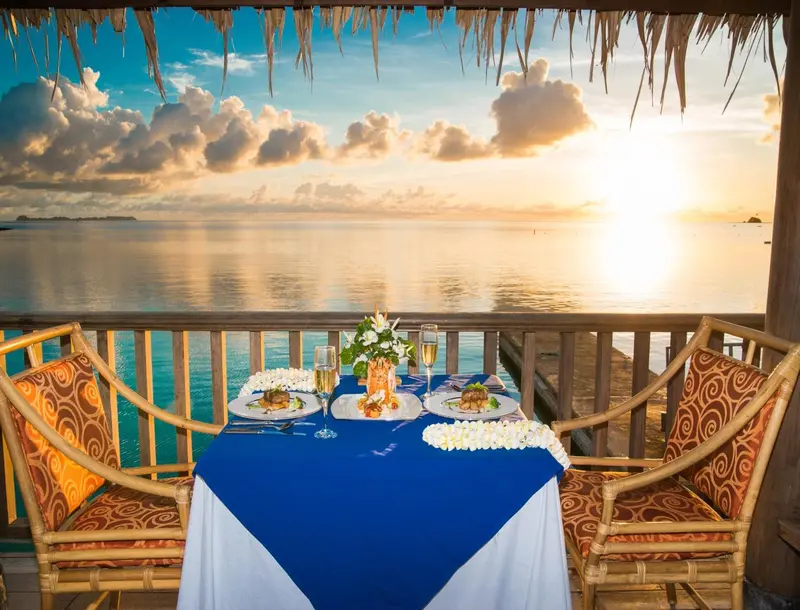 Table dressée pour un dîner romantique avec vue sur la mer au coucher du soleil.