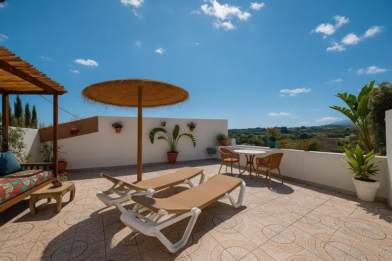 Terrasse aménagée avec transats et mobilier de jardin face à un paysage ensoleillé.