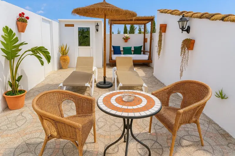Espace extérieur aménagé avec des fauteuils en rotin et un canapé sous un auvent.