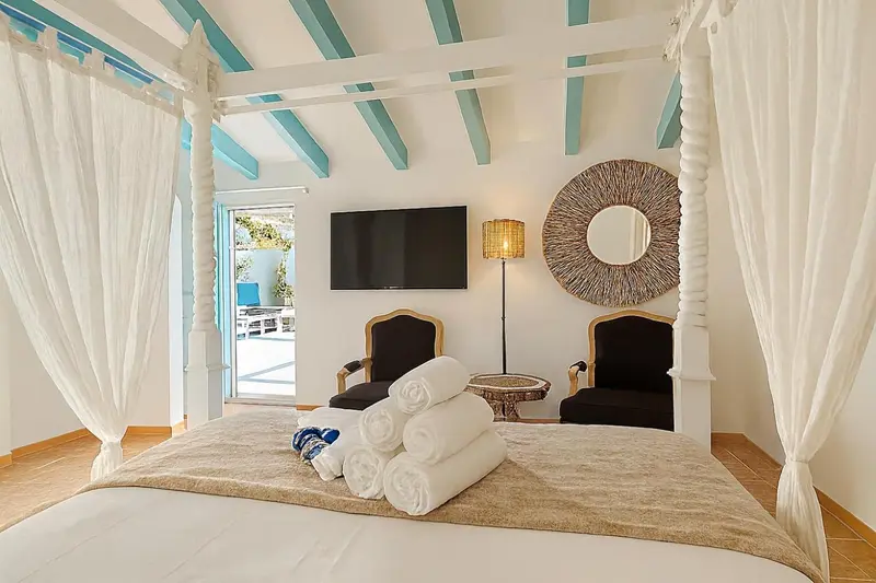 Une chambre lumineuse avec un lit à baldaquin et un accès à une piscine.