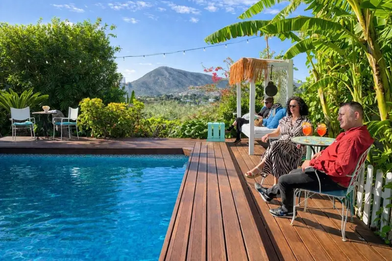 Terrasse en bois avec piscine et végétation luxuriante.