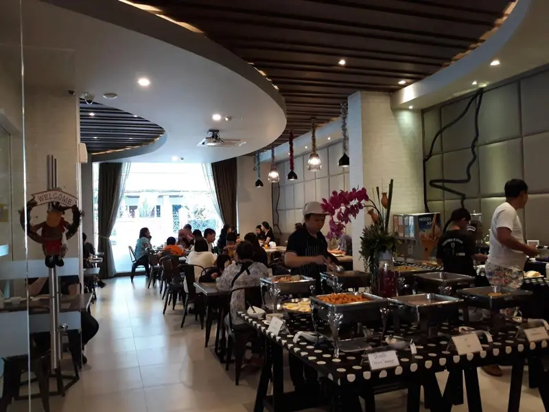 Une salle lumineuse avec des tables et un buffet de nourriture.
