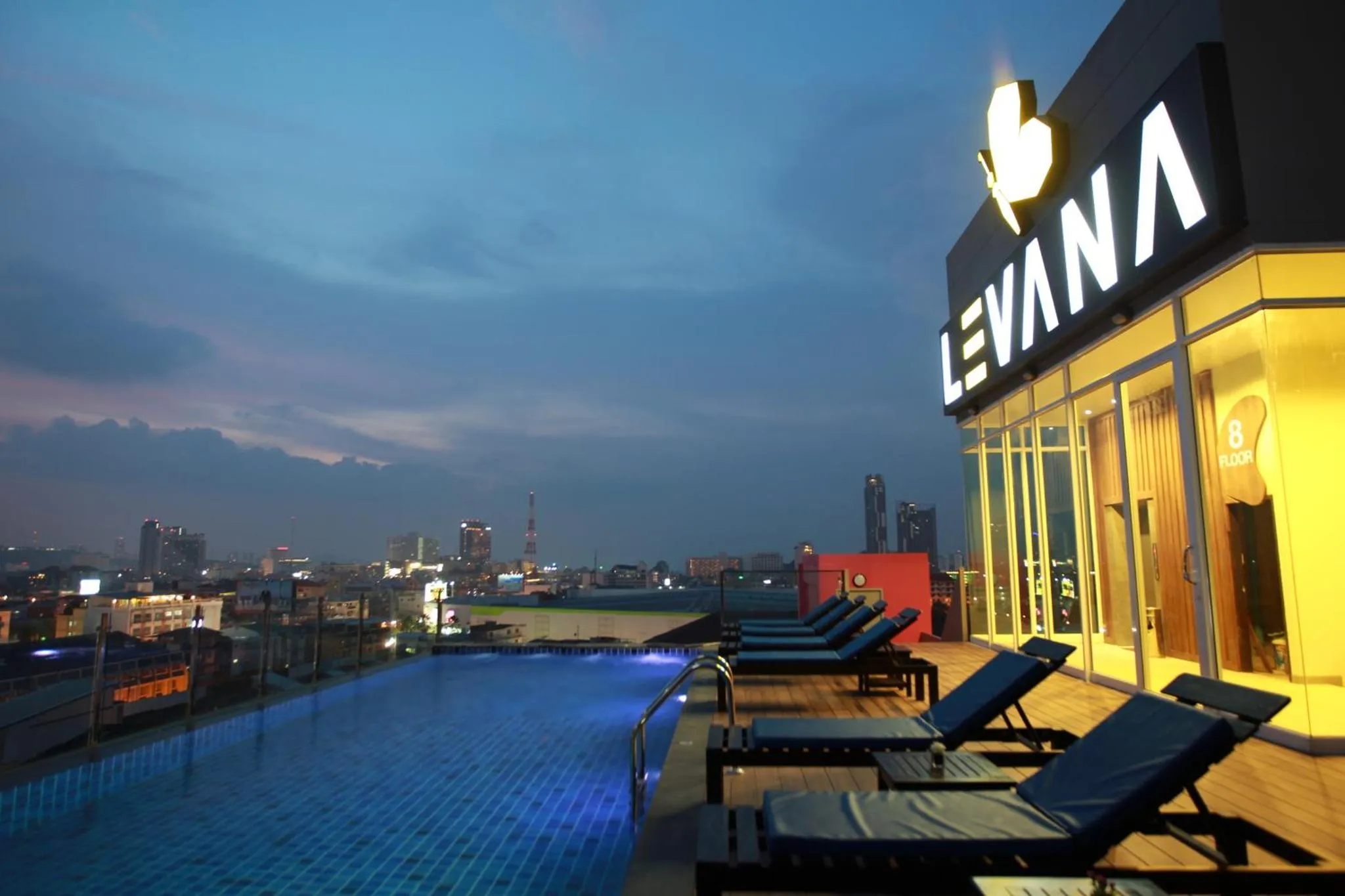 Terrasse avec piscine à débordement et vue sur la ville illuminée.