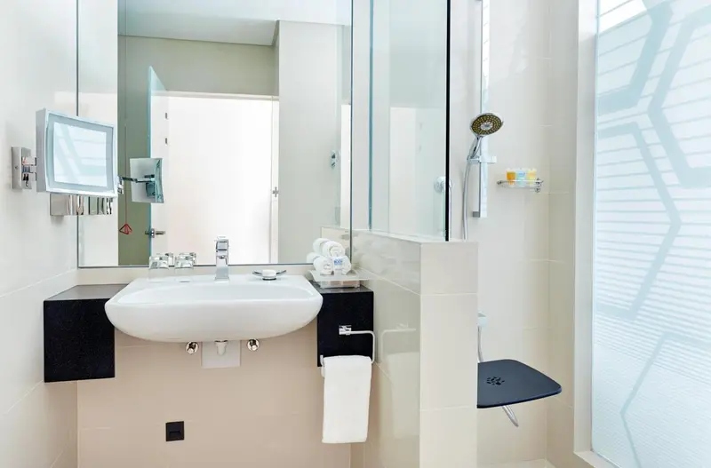 Une salle de bain moderne avec lavabo, miroir et douche à l'italienne.
