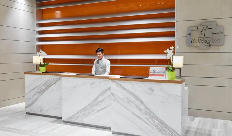 Un employé accueillant se tient derrière un comptoir de réception moderne.