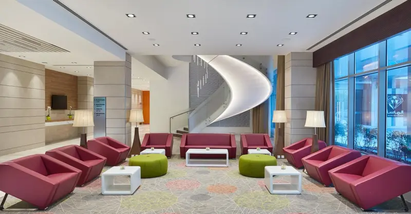 Un espace d'accueil lumineux avec des canapés et des fauteuils colorés.